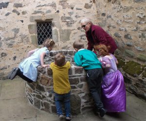 4 young children and a volunteer looking in the well in the courtyard